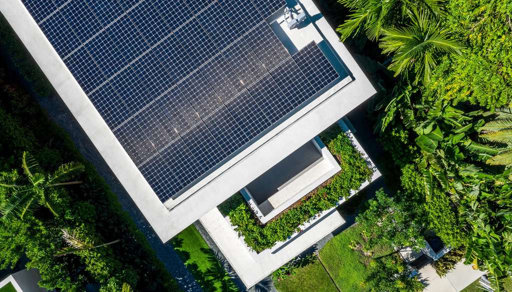 Elevated photovoltaic array forming a ventilated solar canopy above a building roof